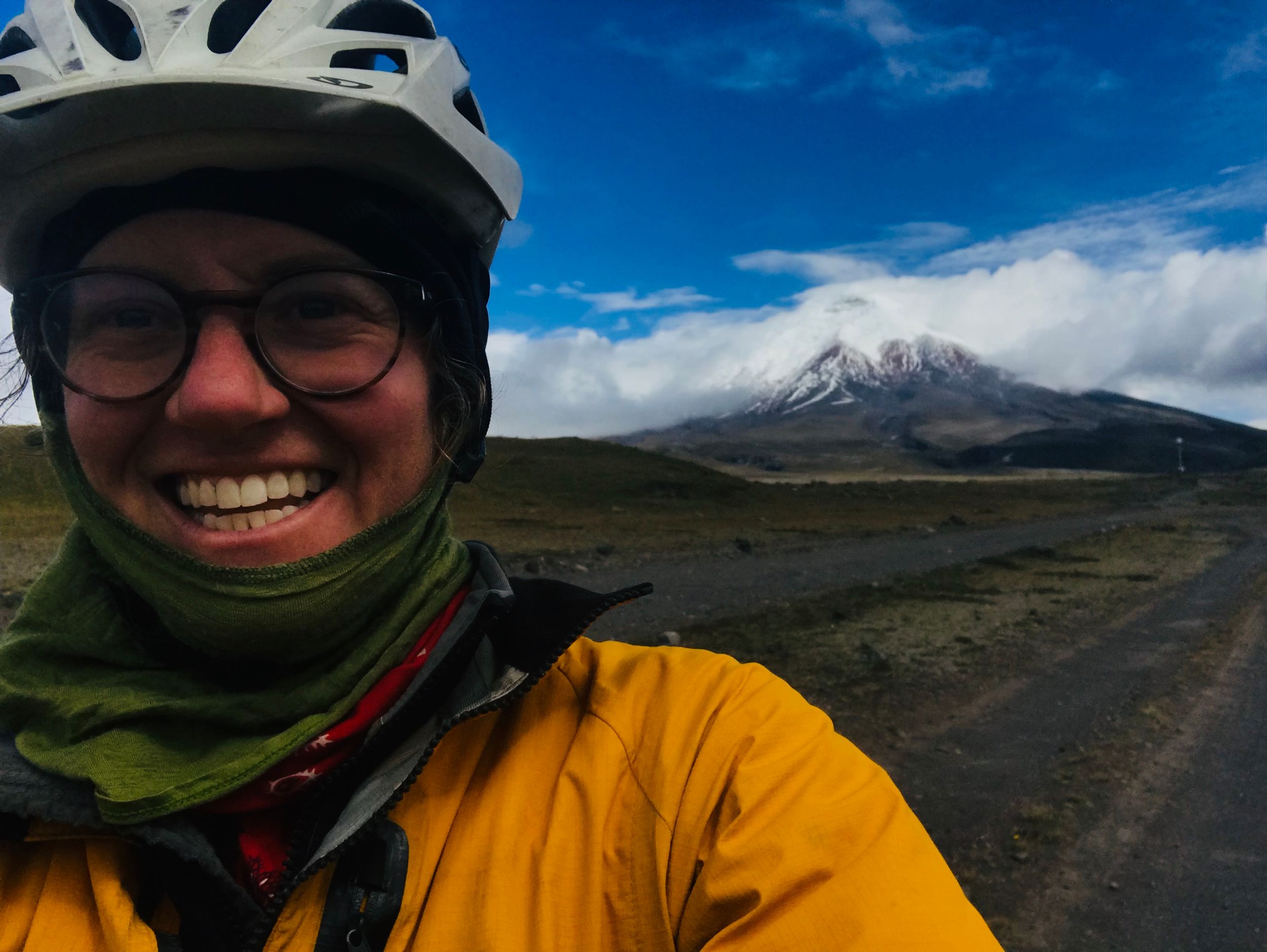 Person smiling and bundled in warm clothes wearing bike helmet.