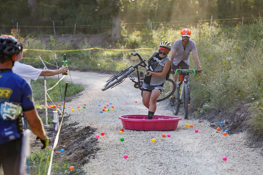 Carmen carrying a bike over a kiddie pool at a bike race