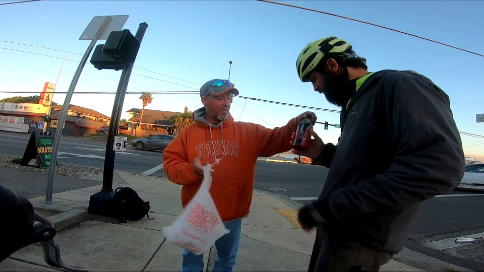 a man hands another man food outside