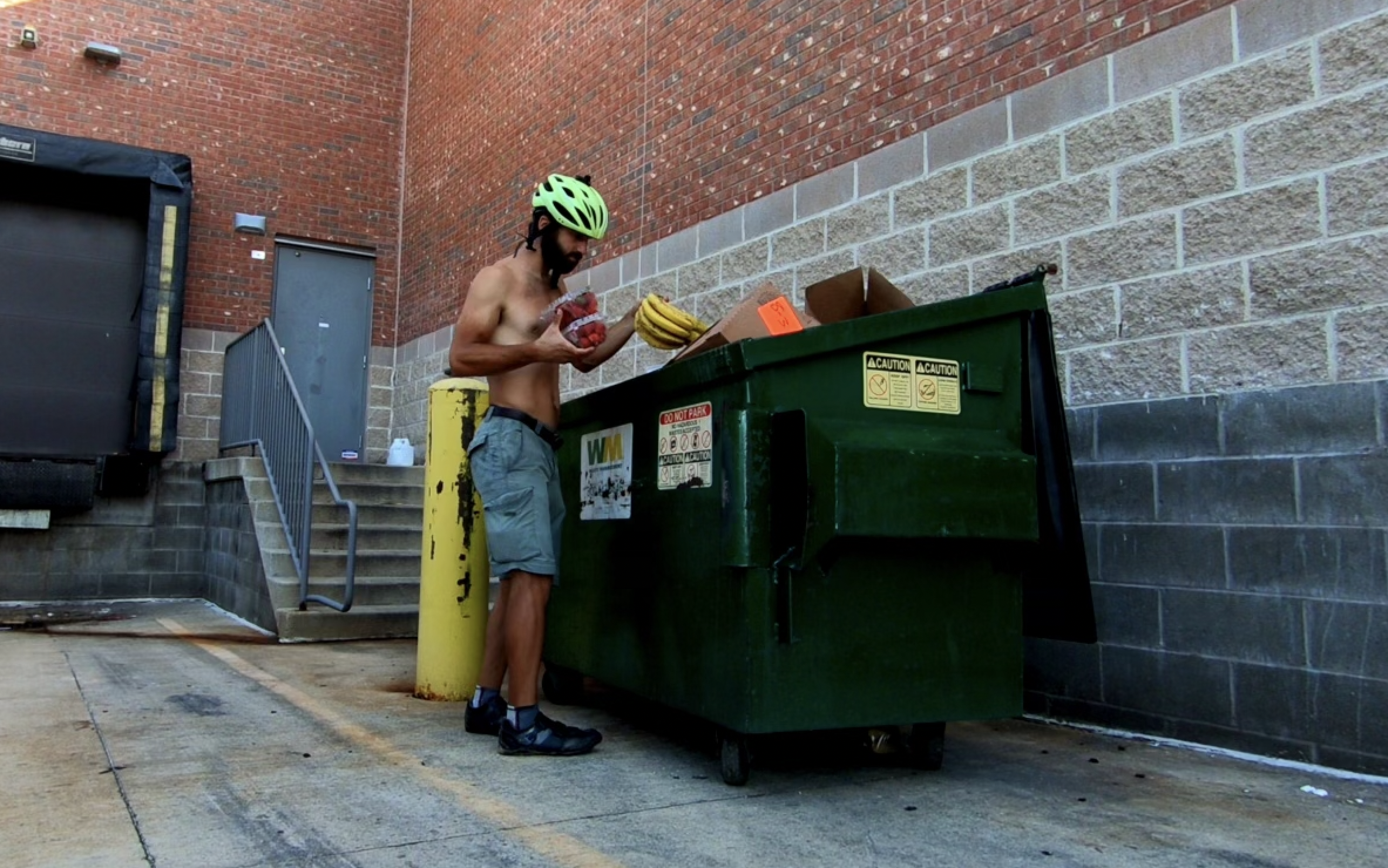 a man in a helmet by a dumpster